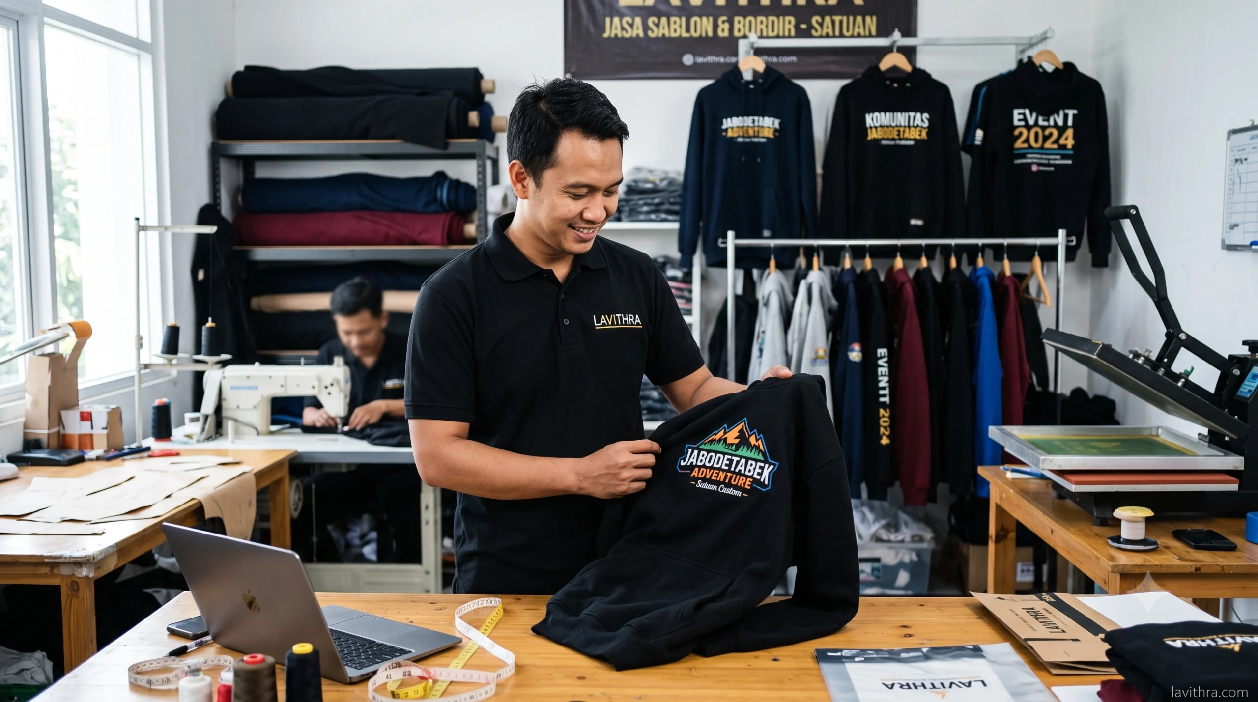 Konveksi Hoodie Custom Fleece Premium Satuan di Jabodetabek 1 Seorang staf konveksi Lavithra sedang mengecek kualitas sablon pada hoodie fleece custom hitam di dalam workshop sablon dan bordir satuan area Jabodetabek.