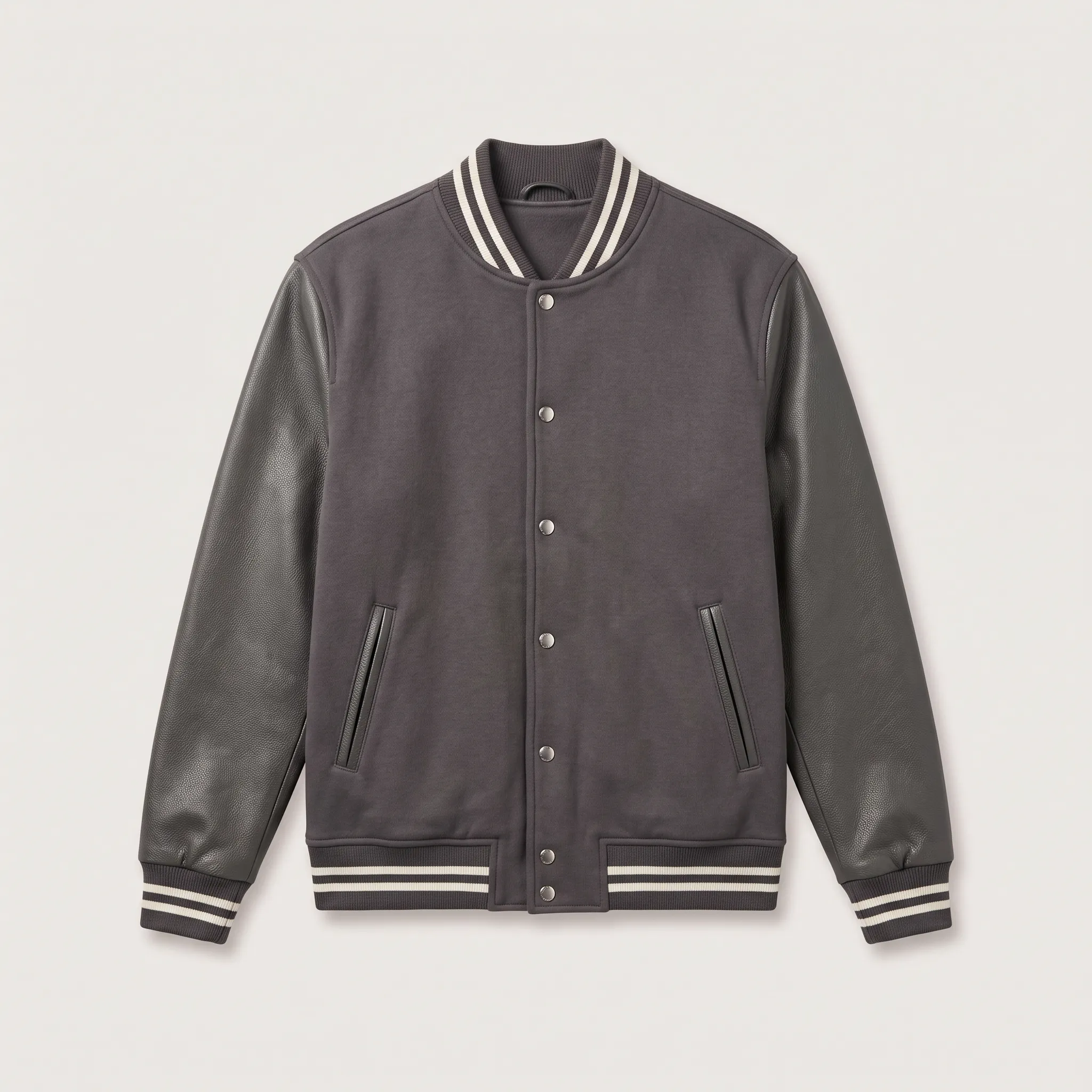 Tampilan depan jaket model varsity atau baseball berwarna abu-abu tua dengan lengan berbahan kulit sintetis berwarna senada, kancing jepret perak, dan detail garis putih pada kerah, manset, dan kelim bawah.