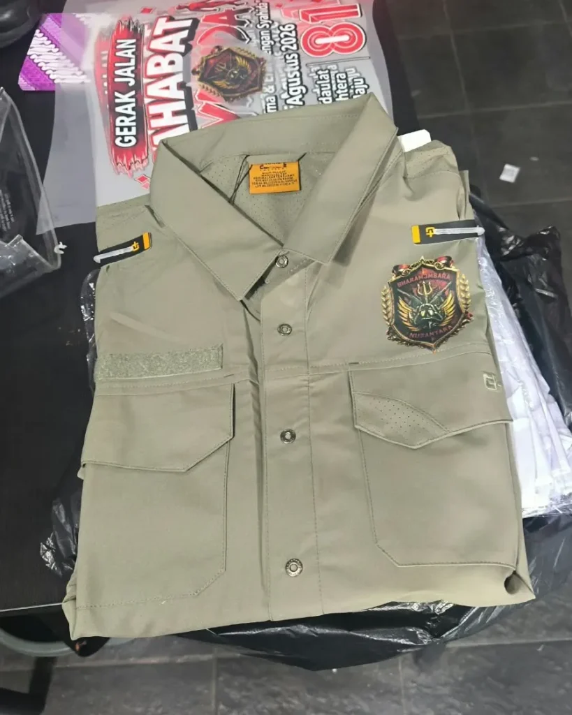 Kemeja lapangan gaya taktikal berwarna krem khaki terlipat rapi dengan emblem bordir bertuliskan "BHARAMBARA NUSANTARA" di saku dada kiri.